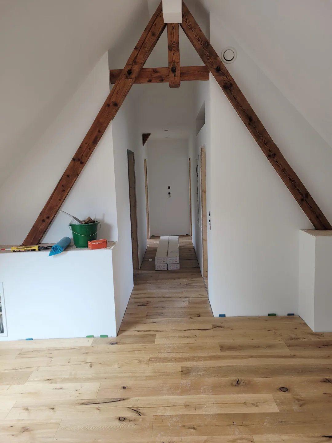 Neu ausgebauter Flur im Dachgeschoss unter einem sichtbaren alten Sparrenpaar, Boden aus Eichendielen