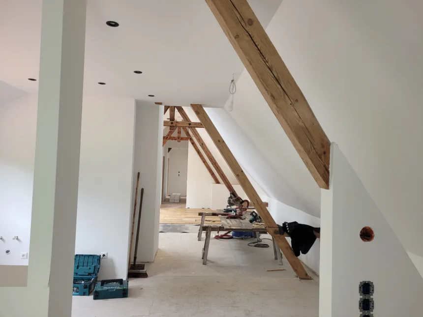 Dachgeschoss im Ausbau: neue Wände und Schrägen, alte Sparren sichtbar, Werkzeug auf dem Boden