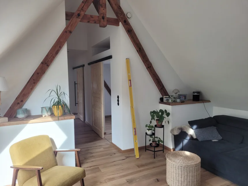 Wohnbereich im Dachgeschoss mit sichtbaren alten Sparren und neuen Wänden