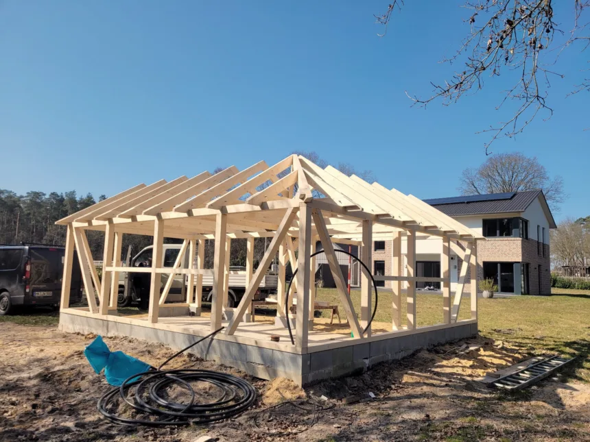 Rohbau eines Carports: Holzständer und Dachstuhl auf der Betonplatte